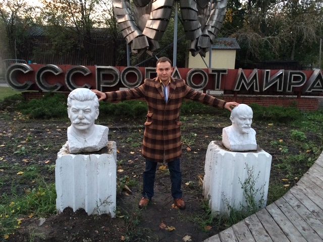Arseny at a Moscow park of Soviet-era monuments, standing between busts of Stalin and Lenin